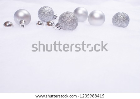 Beautiful shiny and glittering silver baubles on the background of artificial snow cover. New Year and Christmas concept. Copy space.