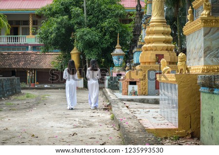 Vietnamese women in traditional dress Ao Dai walking in an ancient Buddhist temple in Southern Vietnam