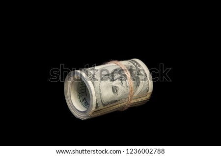 A roll of one hundred dollar bills tied with a rope. On a black background. Isolated