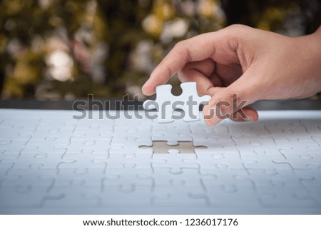 Closeup of woman hands fulfill the last piece of jigsaw puzzle to complete.,Business solutions, success mission concept.