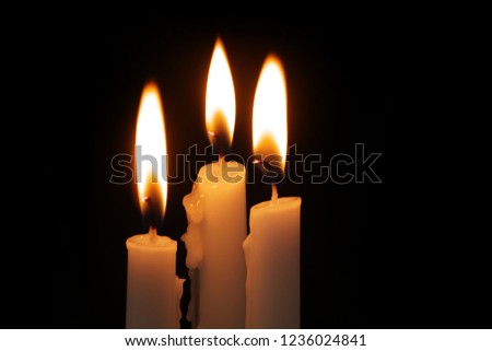 Three burning candles in darkness. Memorial and religion symbol.