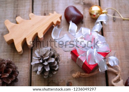 Red gift box and pinecone and small christmas tree on wood table