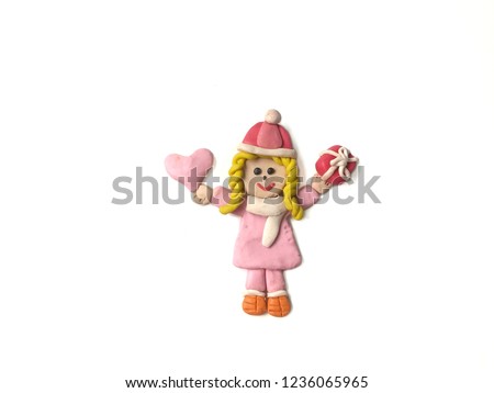 Pretty girl holding the pink heart and red gift box made from plasticine clay placed on white background, cute child dough wearing a coat in winter festival