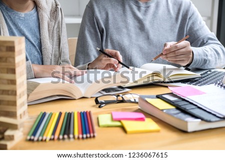 Education, teaching, learning, technology and people concept. Two high school students or classmates with helps friend do homeworks learning in classroom, Tutor books with friends.