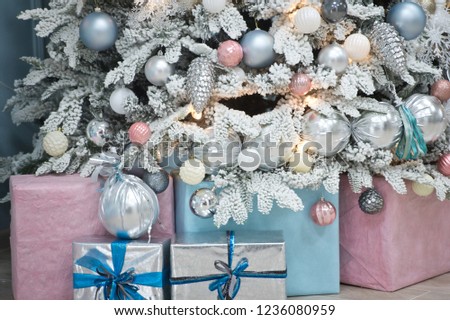 Christmas tree with blue and pink gifts in the white room Christmas. Beautifully decorated house with a silver, pink and blue tree and presents at Christmas.