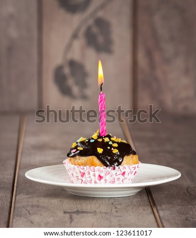 Cupcake with multi colored spinkles and candle on top