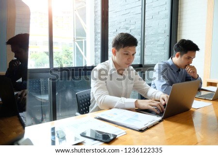 Two businessman working with laptop computer and finance report.