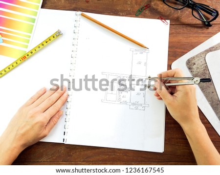 Architect drawing architectural project. Top view on unrecognizable designer hands working with building blueprint