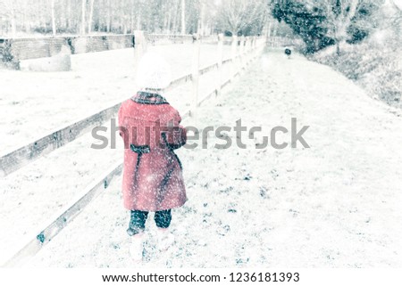 A beautiful little girl playing, walking in the heavy snow fall at Christmas time, Xmas holidays