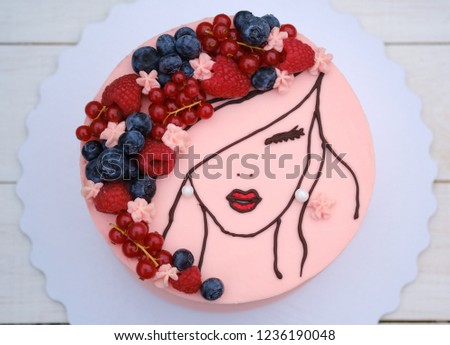 beautiful cake with the image of a girl with fresh berries on her hair and delicate pink cream