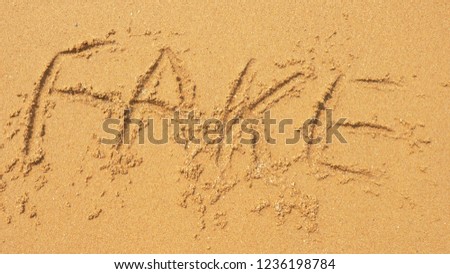 The sea wave erases the inscriptions written on the sand. top view. word fake