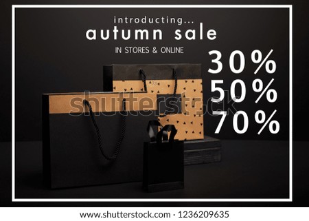 close up view of shopping bags arranged on black background with autumn sale with 30, 50, 70 percents discount