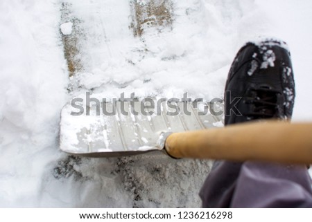 Man using a snow shovel in a snowed front yard