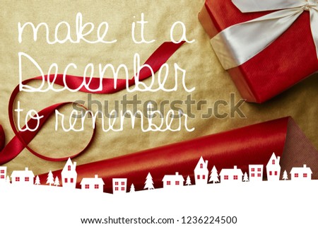 top view of christmas gift and ribbon on red and golden wrapping papers background with "make it a December to remember" inspiration 