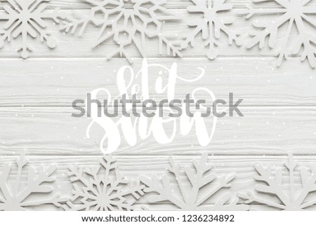 flat lay with decorative snowflakes on white wooden background with "let it snow" lettering