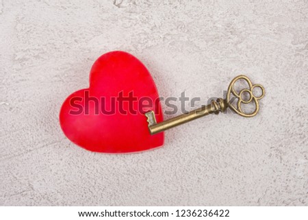 Bright red heart and an old antique key on a gray marble or concrete background (top view) as the Valentine day or love concept