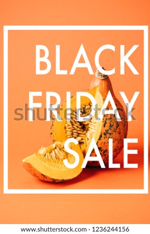 close up view of cut raw pumpkin with black friday sale inscription on orange background