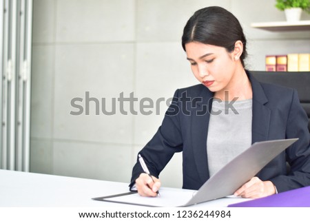 Happy businesswoman signing a contract or document in a desk at office