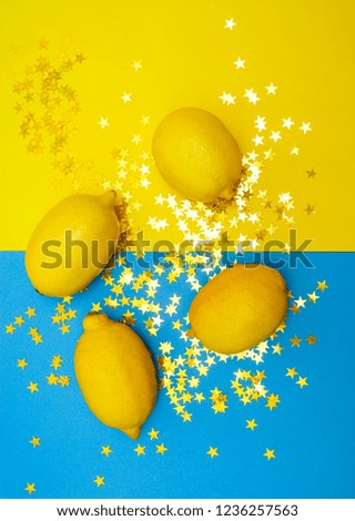 four 4 yellow lemons lie on paper yellow and blue background. food background. golden confetti