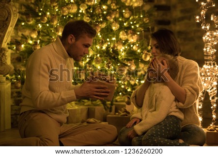 Parents give their daughter a gift near the Christmas tree.