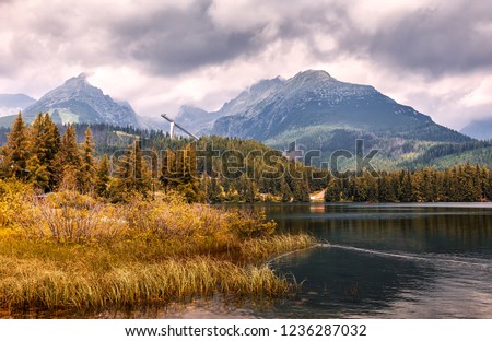 Traditional view to mountain lake Strbske pleso in National Park Vysoke Tatry. Slovakia. Awesome Nature Landscape. Dramatic Scenery, with overcast sky over rockies range near calm lake. Autumn Scenery