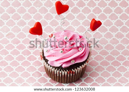 High angle image of strawberry cupcake with heart shape and beads.