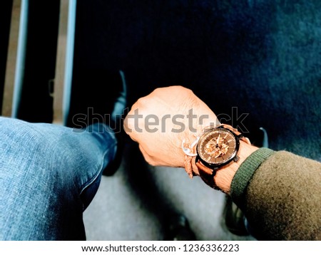 A close-up picture of a man's wrist wearing a stylish cognac brown bracelet and brown mechanical watch with black bezel and brown crown. 