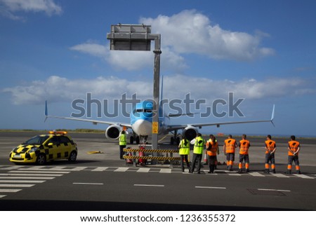 Airport arrival of an airplane, ground crew waiting with safety jackets on until the Apron Officer is ready to guide the pilot to his parking space
