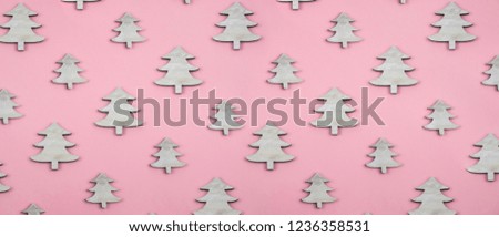 Creative and minimal  Christmas pattern made of wooden christmas trees. Pink background. Flat lay top view.