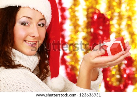 Happy woman in santa hat with gift box isolated on christmas decorated background