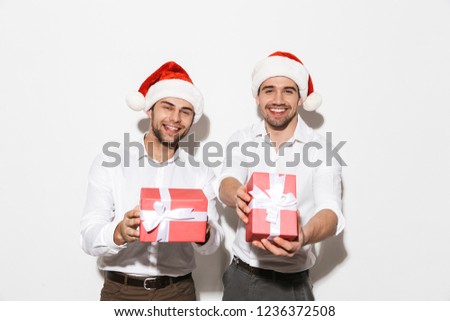 Two cheerful smartly dressed men standing isolated over white background, celebrating New Year, holding present boxes