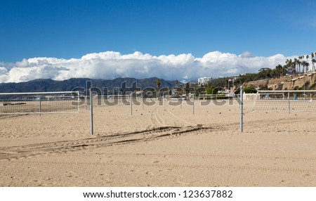 Rows of empty beach volleyball courts in Santa Monica California with mountains in background