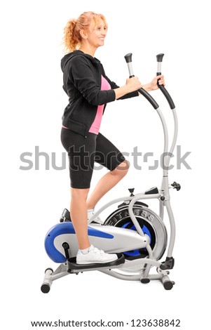 Full length portrait of a mature woman excersing on a cross trainer isolated on white background