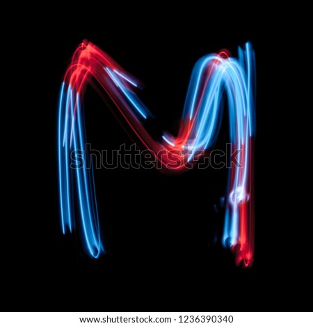 Letter M of the alphabet made from neon sign. The blue light image, long exposure with colored fairy lights, against a black background