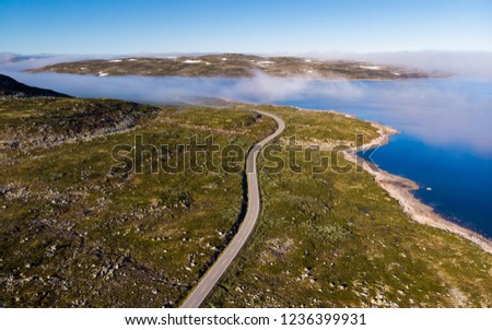 Aerial view. Road crossing Hardangervidda mountain plateau, clouds over lakes, morning time. Norway landscape. National tourist Hardangervidda route.