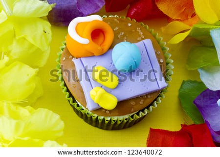 Close-up image of a cupcake with decorative miniature toppings surrounded by colorful flowers.