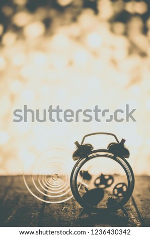 Broken alarm clock with springs and gears scattered on the background of bright light.