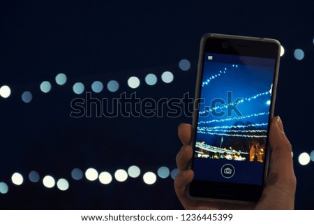 A girl photographing Christmas lights on a smartphone's camera, City, Holidays, New Year