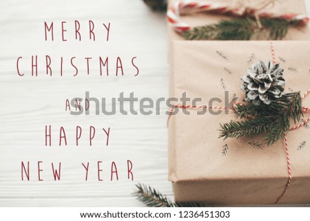 Merry Christmas and Happy New Year text on christmas stylish presents with red ribbon, candy cane, pine branches and cones. Season's greetings card. Happy Holidays