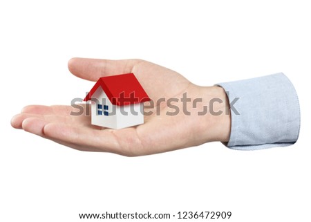 Hand holding a small red roofed house, isolated on white background