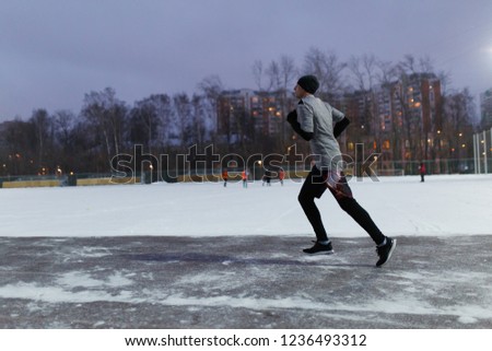 Photo of man in black sports clothes running in winter park