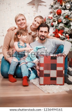 New Year's picture of parents with daughters on background of decorated pine