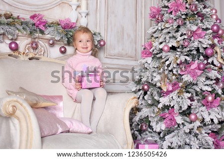 Happy little girl with toys at home sitting near Christmas tree. Happy Family consept.