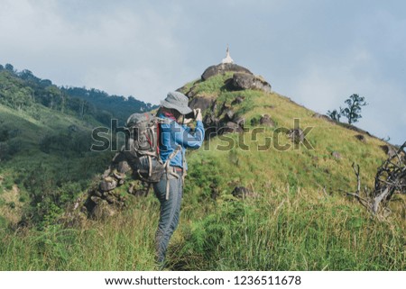 Asian women backpacks on mountain and happy are taking photo and looking picture ,Relax time on holiday concept travel
