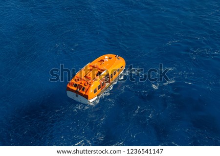 Orange rescue boat on blue sea waves background. Aerial view
