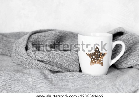 cute white cup with drink and gray knitted sweaters and scarf, cozy autumn  or winter weekends concept
