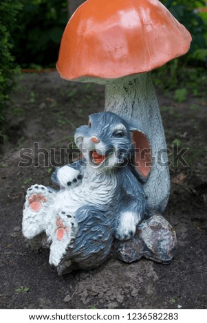 Easter bunny and colorful Easter eggs on the garden. Rabbit statuette. Easter egg hunt concept.