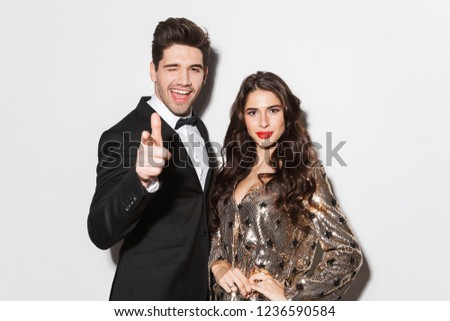 Cheerful young smartly dressed couple celebrating New Year party isolated over white background