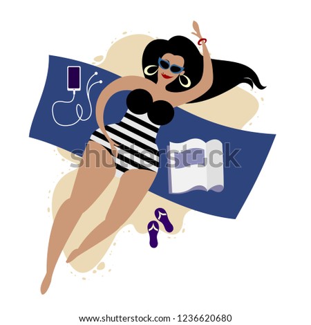 body-positive plus size cute girl in a striped swimsuit with a phone and a magazine on the blanket takes a sunbath nearby the sea