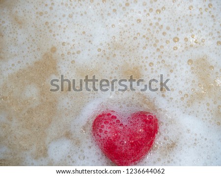 Picture of red heart wet on the beach sand.